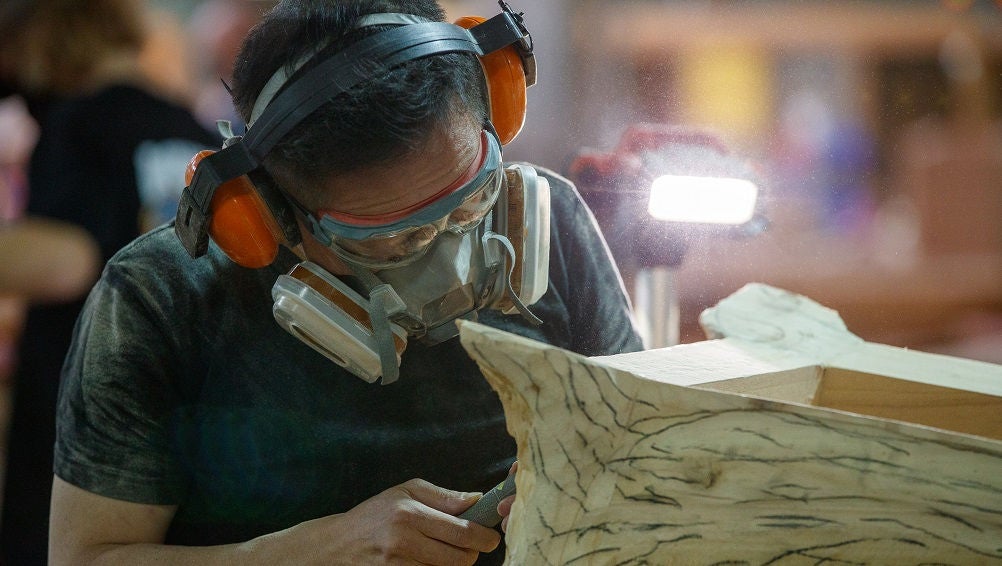 Student works on furniture piece in workshop.