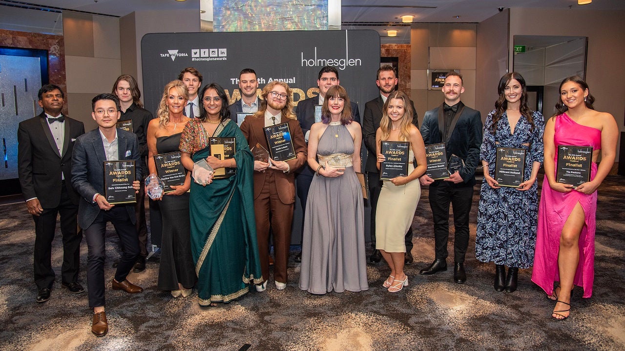 Holmesglen student award winners pose in a group photo, holding their certificates.