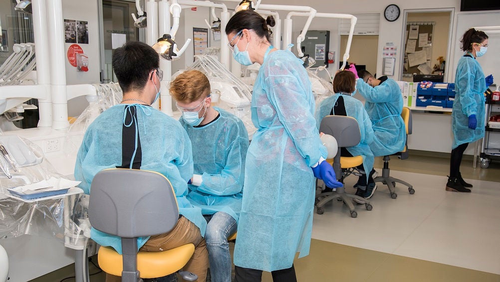 Dental student use a medical dummy to practice a dental exercise in a training lab.