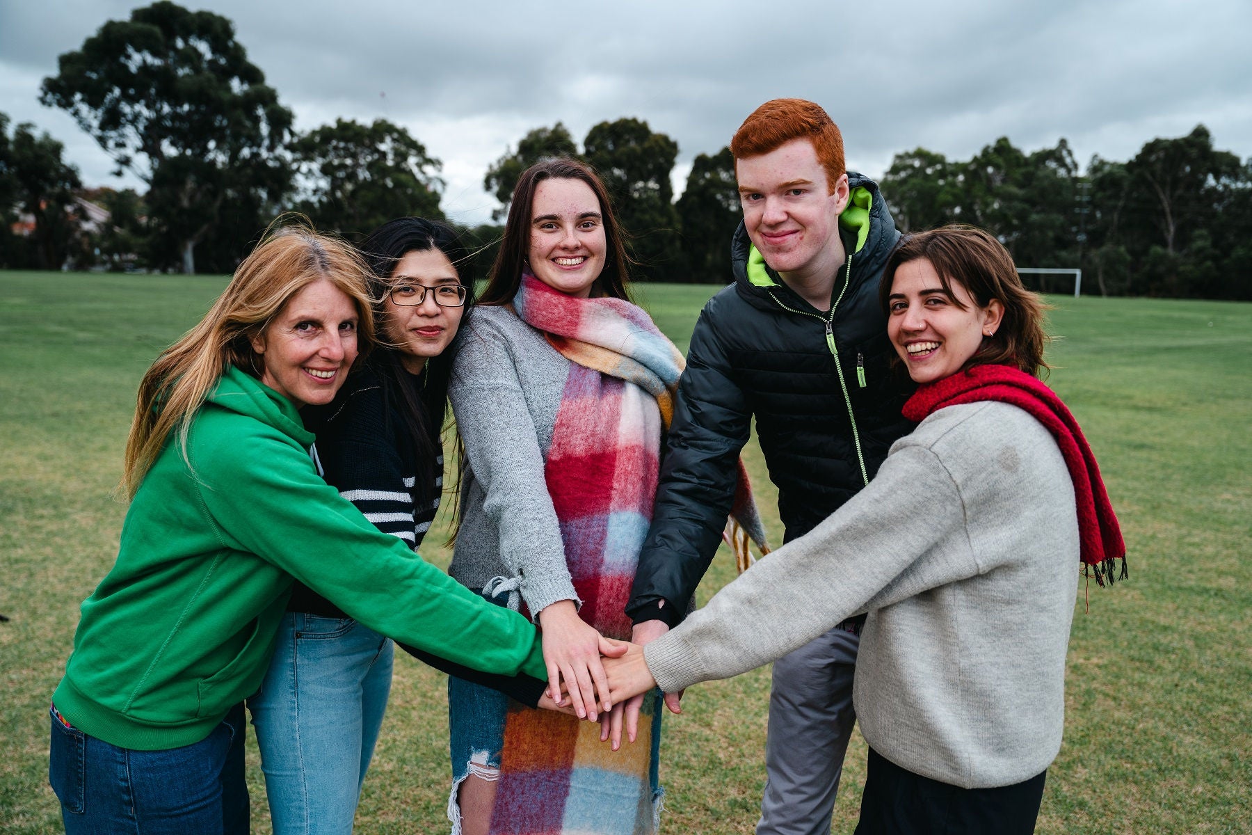 Five smiling students stand together on an oval.