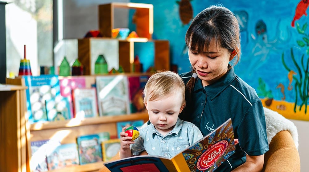 Image of a Holmesglen student reading a book to a child.