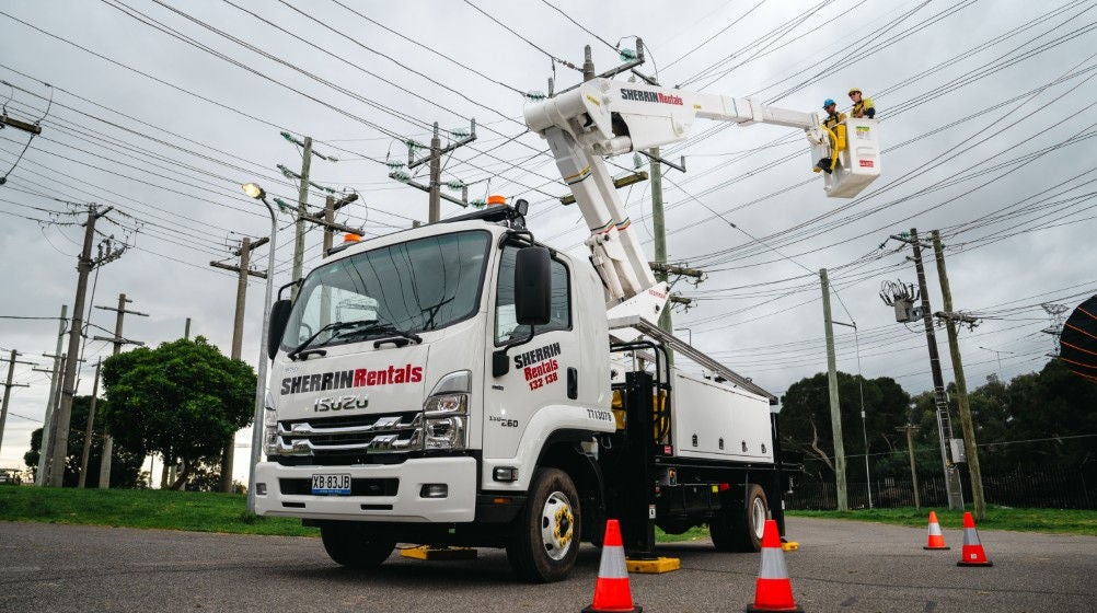 Two people in a crane working on an overhead powerline at holmesglen