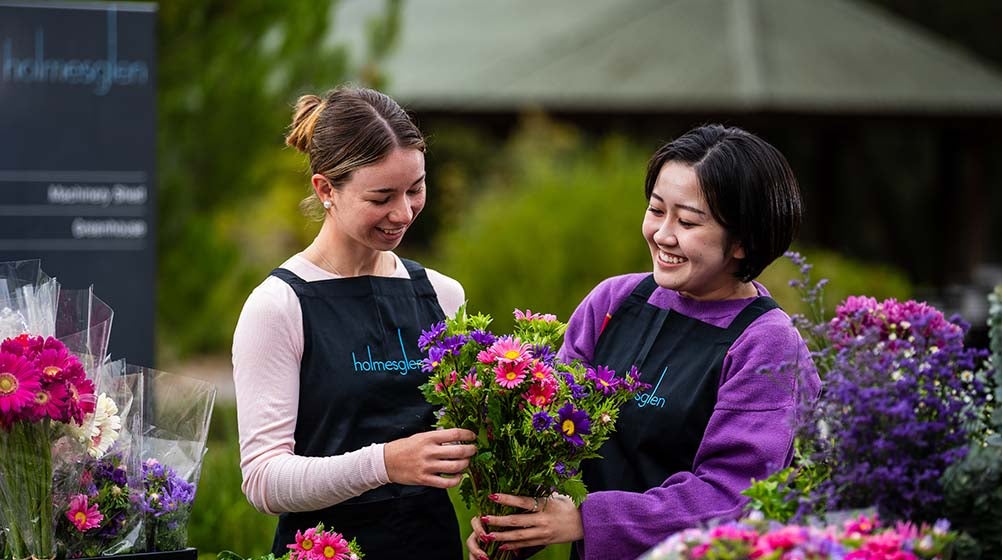 Photo of two Holmesglen students holding a potted flower.
