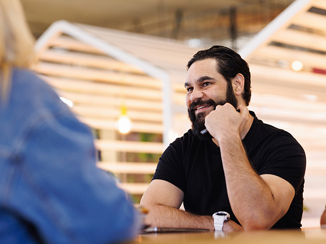 Aboriginal Australian man at meeting with Indigenous colleagues in creative modern workspace.