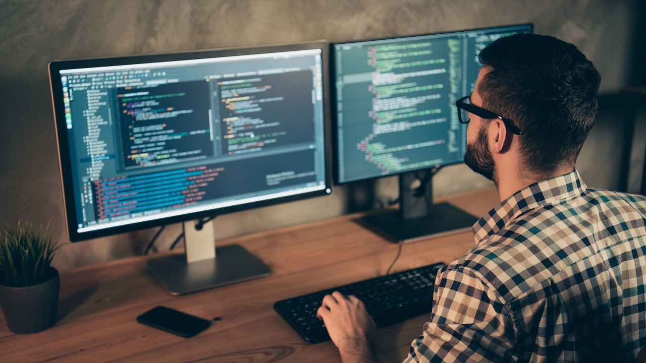 Professional worker sits at their desk, looking at a work computer screen.