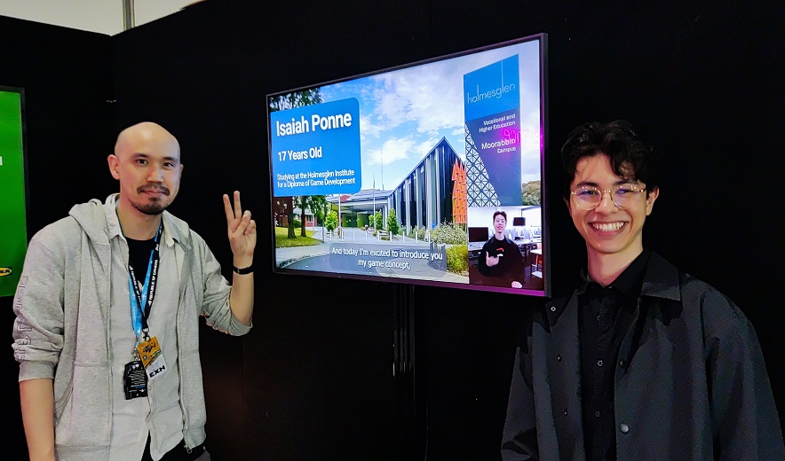 A teacher and student stand in front of an interactive screen at an expo event.