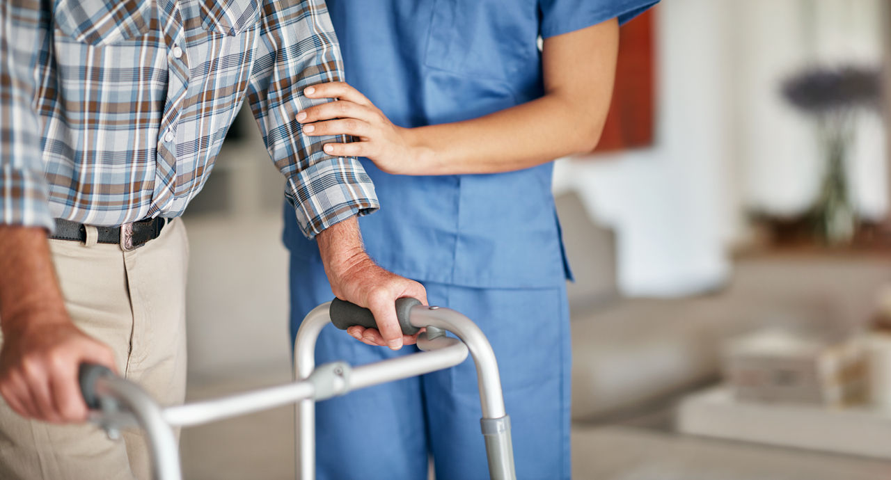Shot of a woman assisting her elderly patient who's using a walker for support