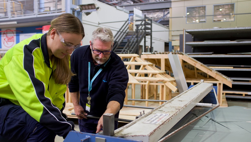 Teacher supports plumbing student when using equipment.