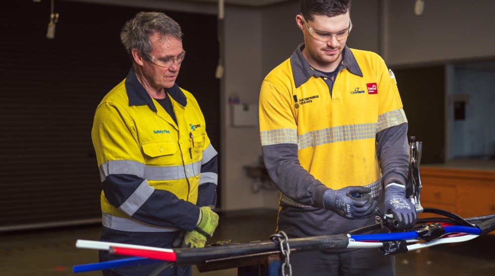 A student is being trained by a trainer on how to join cables.