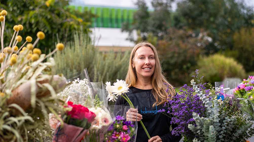Photo of a Holmesglen student holding a white flower