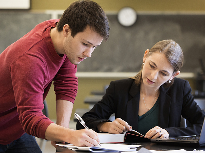 Caucasian student and teacher studying in classroom